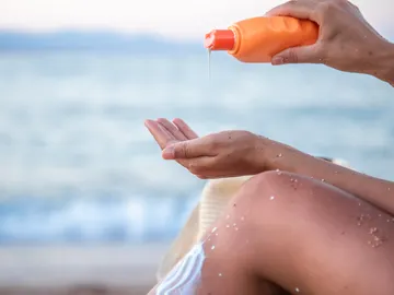 Mujer en la playa con crema solar Mujer en la playa con crema solar