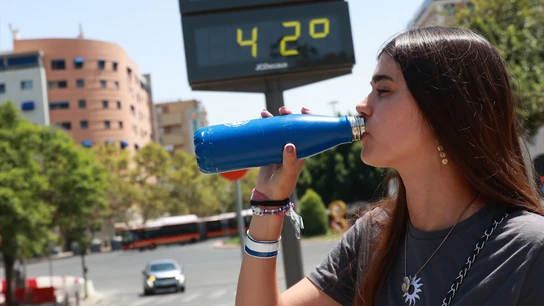 Una joven bebe agua en plena ola de calor. Una joven bebe agua en plena ola de calor.
