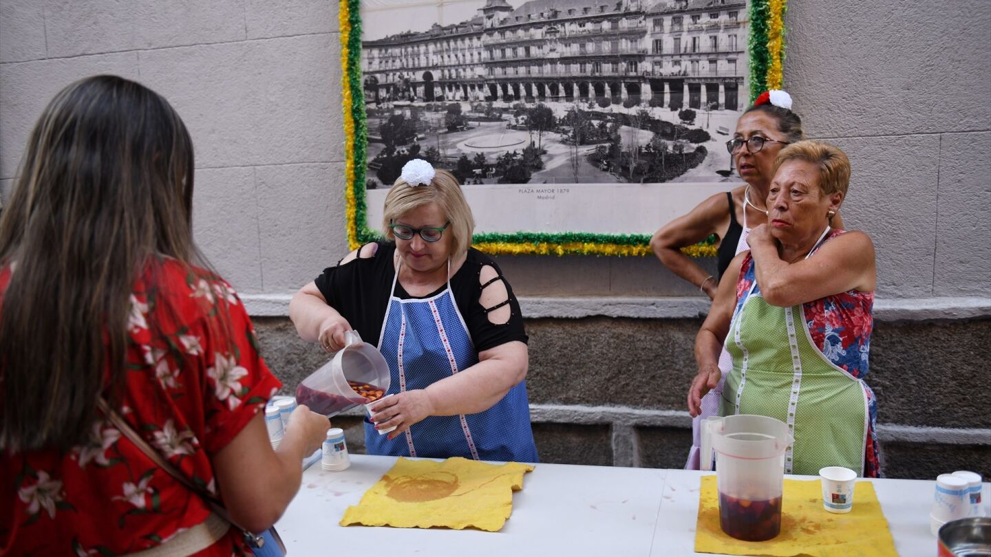 Varias mujeres reparten bebida gratuita en la Calle del Oso de Madrid durante las fiestas de San Cayetano.