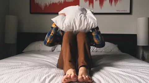 Persona cubriéndose la cabeza con una almohada Persona cubriéndose la cabeza con una almohada