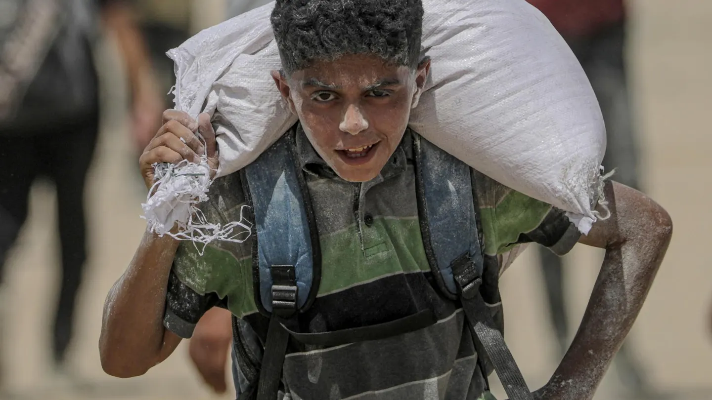Un joven palestino lleva una bolsa de harina cerca de un punto de distribución de alimentos en Zikim, en la Franja de Gaza. Un joven palestino lleva una bolsa de harina cerca de un punto de distribución de alimentos en Zikim, en la Franja de Gaza.