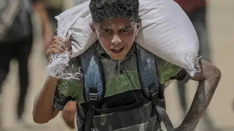 Un joven palestino lleva una bolsa de harina cerca de un punto de distribución de alimentos en Zikim, en la Franja de Gaza. Un joven palestino lleva una bolsa de harina cerca de un punto de distribución de alimentos en Zikim, en la Franja de Gaza.