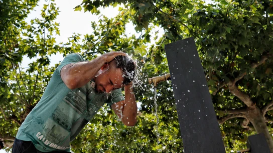 Una persona se refresca en una fuente Una persona se refresca en una fuente