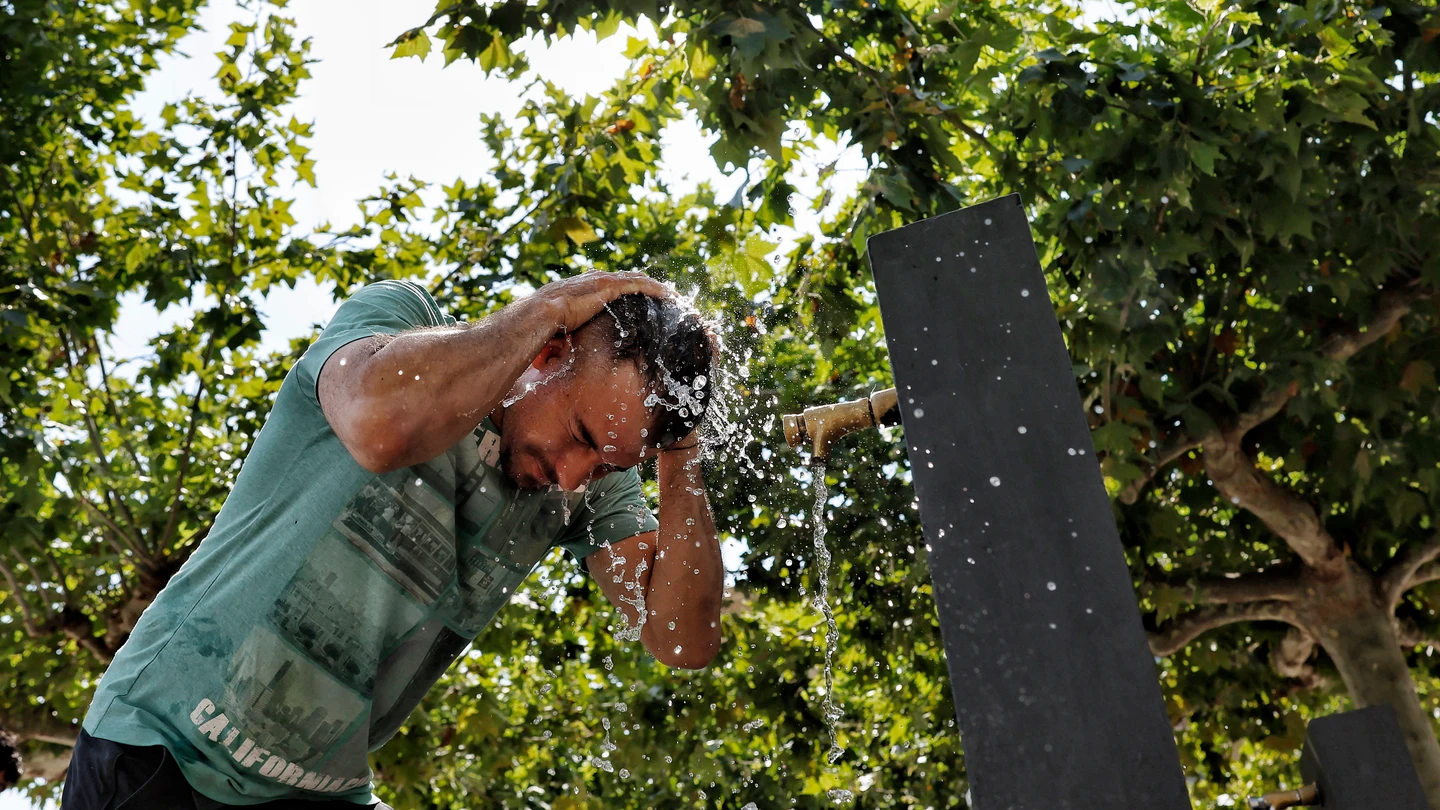 Una persona se refresca en una fuente Una persona se refresca en una fuente