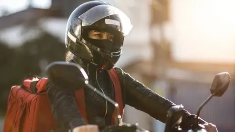 Conductora de una motocicleta con una máscara Conductora de una motocicleta con una máscara