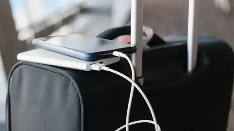 Pasajero cargando el móvil con una batería externa Pasajero cargando el móvil con una batería externa