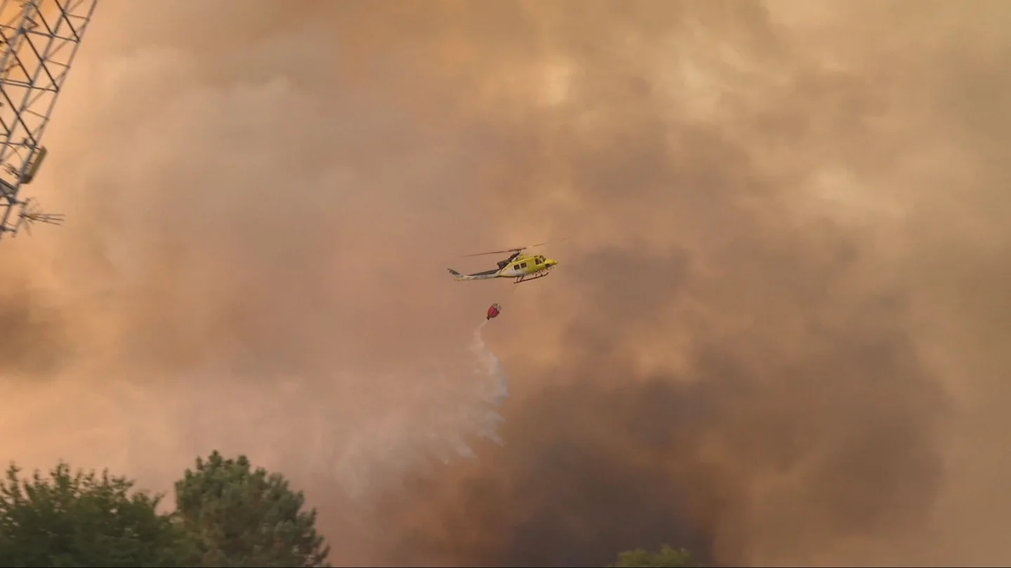 Un helicóptero echa agua sobre un incendio Un helicóptero echa agua sobre un incendio