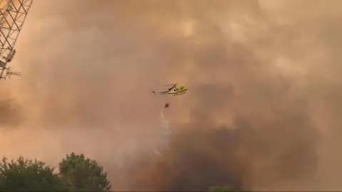 Un helicóptero echa agua sobre un incendio Un helicóptero echa agua sobre un incendio