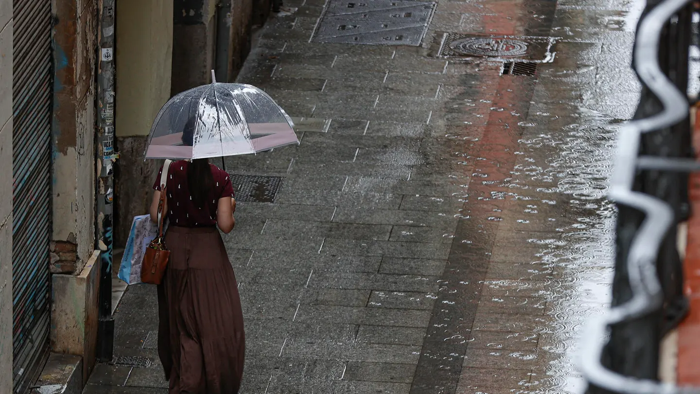 Una persona camina bajo la lluvia. Una persona camina bajo la lluvia.