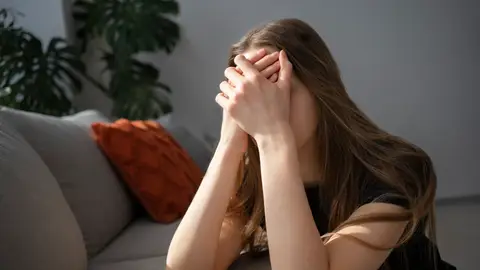 Una mujer tapándose la cara por ansiedad Una mujer tapándose la cara por ansiedad