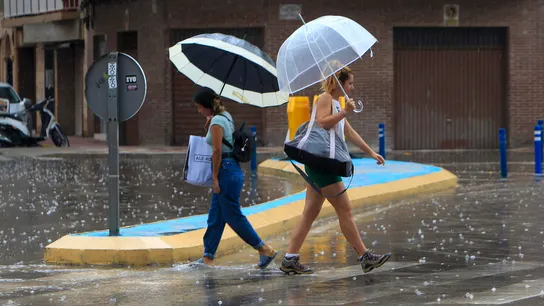 Dos personas caminan bajo un paraguas Dos personas caminan bajo un paraguas