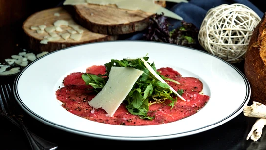 Un plato con carpaccio, acompañado de rúcula y parmesano Un plato con carpaccio, acompañado de rúcula y parmesano