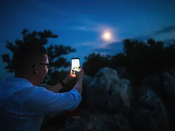 Hombre fotografiando la Luna con el móvil Hombre fotografiando la Luna con el móvil
