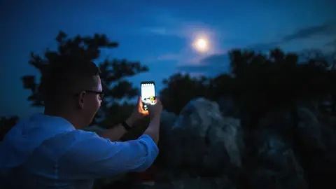 Hombre fotografiando la Luna con el móvil Hombre fotografiando la Luna con el móvil