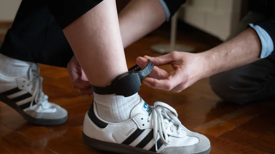 Una persona le coloca a otra una pulsera electrónica de geolocalización telemática Una persona le coloca a otra una pulsera electrónica de geolocalización telemática