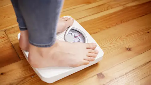 Persona sobre una báscula Persona sobre una báscula
