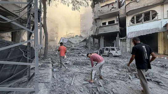 Varios hombres caminan bajo los escombros de un edificio destruido por Israel Varios hombres caminan bajo los escombros de un edificio destruido por Israel
