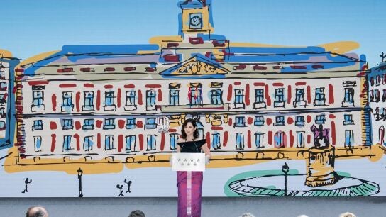 La presidenta de la Comunidad de Madrid, Isabel D&iacute;az Ayuso, con una imagen pintada de la Casa Real de Correos