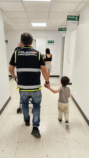 Imagen de uno de los niños junto a un policía Imagen de uno de los niños junto a un policía