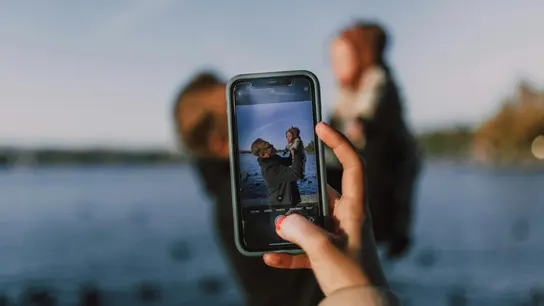 Una persona hace una foto a un hombre y un bebé con el móvil Una persona hace una foto a un hombre y un bebé con el móvil