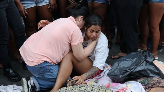 Una mujer llora desconsolada ante el cadáver de un familiar mientras otra persona trata de consolarla en Río de Janeiro (Brasil).