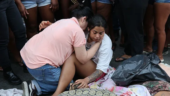 Los habitantes de Penha buscan a sus seres queridos en la fila de cadáveres del Complejo da Penha. Una mujer llora desconsolada ante el cadáver de un familiar mientras otra persona trata de consolarla en Río de Janeiro (Brasil).