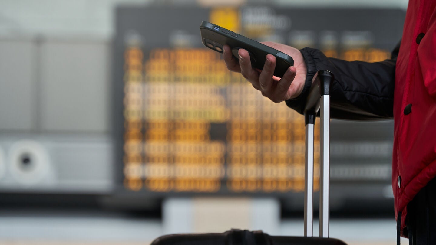 Chico con el tel&eacute;fono m&oacute;vil en el aeropuerto