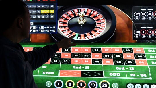 Un hombre est&aacute; de pie frente a una pantalla con una p&aacute;gina de ruleta online.