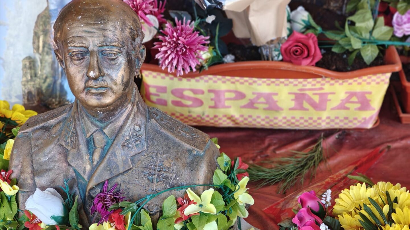 Un busto de Franco junto a multitud de flores y un banderón de España en el cementerio de Mingorrubio, el día del 50.º aniversario de la muerte de Franco