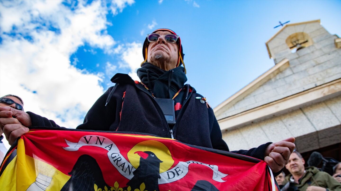 Un hombre sostiene una bandera franquista durante un homenaje organizado por el Movimiento Católico Español frente a la tumba de Franco en el cementerio de Mingorrubio, a 20 de noviembre de 2025, en Madrid (España).