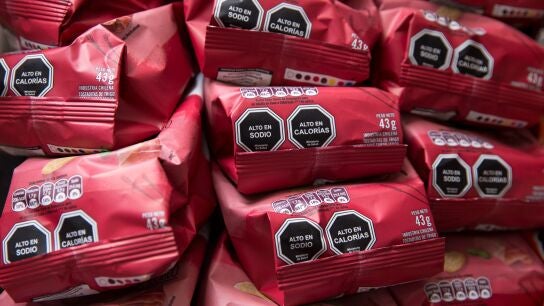 Imagen de archivo de una pared repleta de paquetes de patatas fritas con sellos de advertencia alimentaria