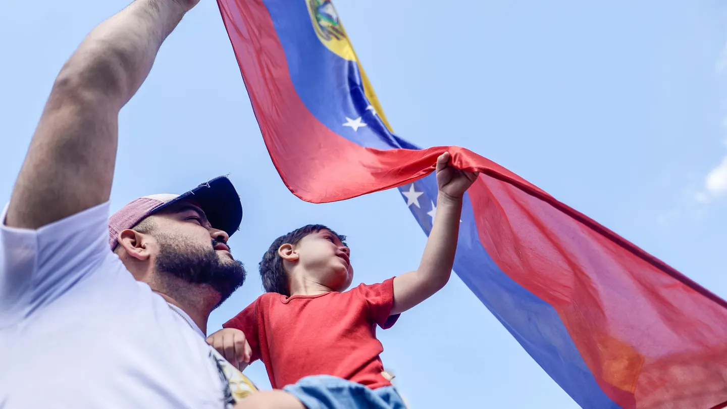 Un padre venezolano protesta junto a su hijo con la bandera de su país Un padre venezolano protesta junto a su hijo con la bandera de su país