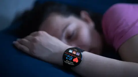 Mujer durmiendo con reloj inteligente Mujer durmiendo con reloj inteligente