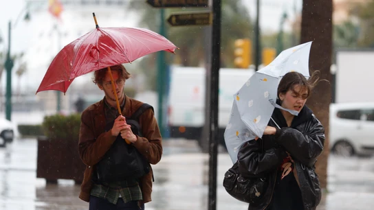 Varias personas luchan contra el fuerte viento que se registra este miércoles en Málaga Varias personas luchan contra el fuerte viento que se registra este miércoles en Málaga