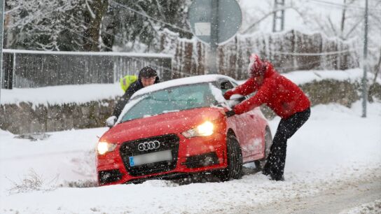 Varias personas tratan de sacar un coche de la nieve