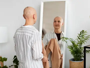 Una mujer en tratamiento contra el cáncer se mira al espejo Una mujer en tratamiento contra el cáncer se mira al espejo