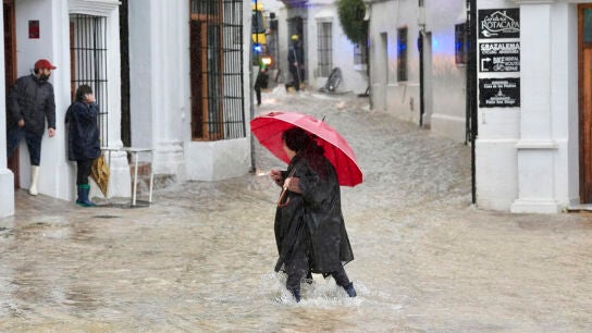 Una vecina de Grazalema (C&aacute;diz) camina por una calle inundada debido a las intensas lluvias que se registran este mi&eacute;rcoles en la localidad gaditana.