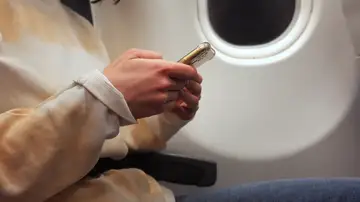 Persona usando el móvil en un avión Persona usando el móvil en un avión
