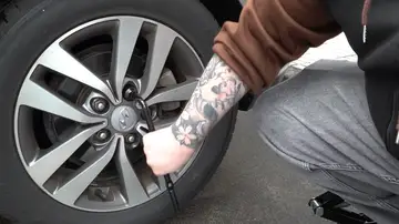 Hombre cambiando una rueda Hombre cambiando una rueda