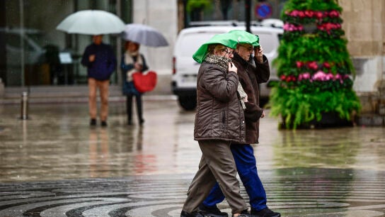 En la imagen varias personas caminan bajo la lluvia por las calles del centro de Castell&oacute;n.