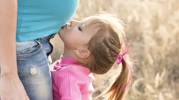 Una niña besando la barriga embarazada de su madre Una niña besando la barriga embarazada de su madre