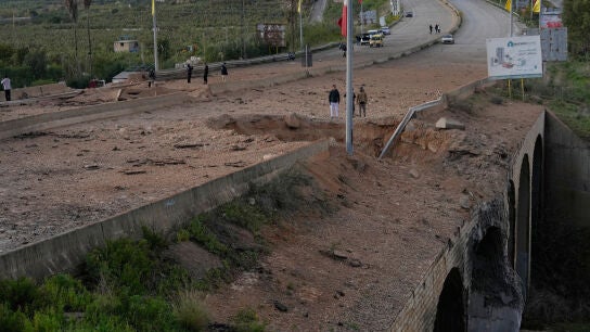 Varias personas inspeccionan un cr&aacute;ter tras un ataque a&eacute;reo israel&iacute; que impact&oacute; el puente Qasmiyeh, cerca de la ciudad costera de Tiro, L&iacute;bano
