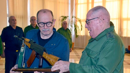 El cantautor cubano Silvio Rodr&iacute;guez (i) sosteniendo un fusil junto al ministro de las Fuerzas Armadas Revolucionarias de Cuba, &Aacute;lvaro L&oacute;pez Miera