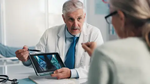 Médico experto hablando con paciente de sus huesos Médico experto hablando con paciente de sus huesos