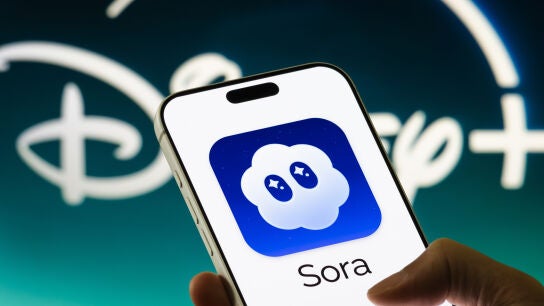 Un tel&eacute;fono m&oacute;vil con el logo de Sora frente a un fondo con el logo de Disney