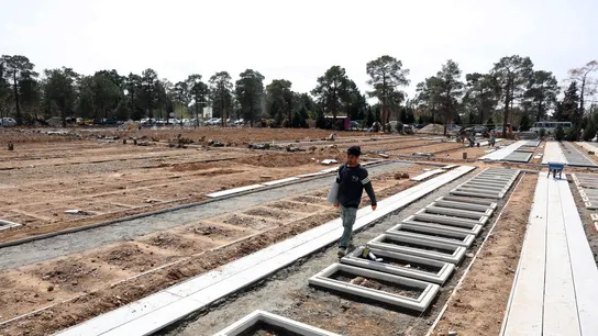 Un trabajador iraní camina sobre las sepulturas preparadas para las víctimas de la guerra Un trabajador iraní camina sobre las sepulturas preparadas para las víctimas de la guerra