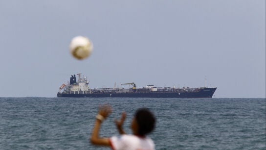 Un joven juega con una pelota en la playa mientras el buque Sea Horse, con bandera de Hong Kong, que transporta unos 200.000 barriles de combustible de origen ruso con destino original a Cuba