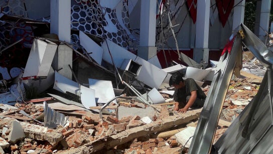 Un hombre inspecciona los escombros en el lugar donde qued&oacute; un edificio da&ntilde;ado tras un terremoto en Manado.