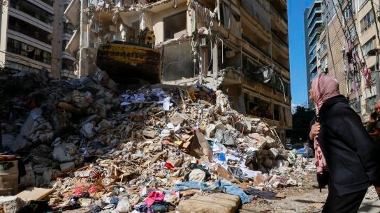 Una mujer observa c&oacute;mo un bulldozer trata de limpiar un edificio destruido en un barrio de Beirut, en L&iacute;bano.