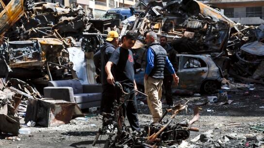 Personas caminan entre los restos de autom&oacute;viles en Corniche el Mazraa, una de las zonas afectadas por la oleada masiva de ataques a&eacute;reos israel&iacute;es en Beirut.